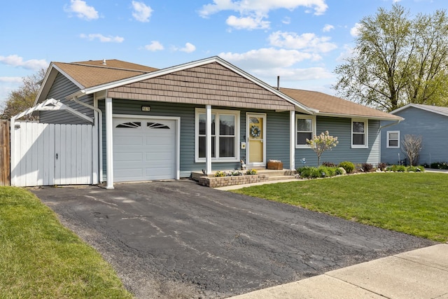 single story home featuring a front lawn, fence, roof with shingles, an attached garage, and driveway