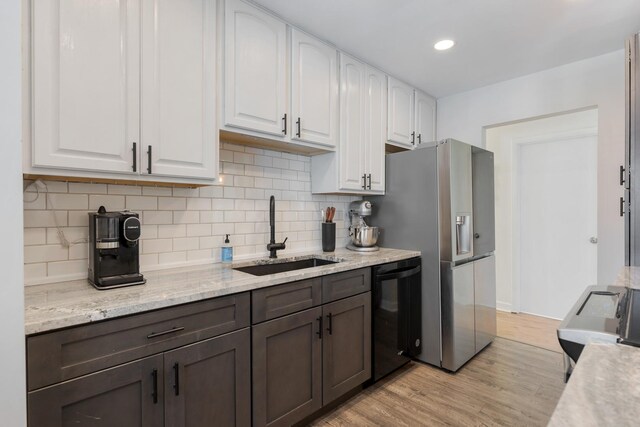 kitchen featuring a sink, light wood-style flooring, black dishwasher, and white cabinetry