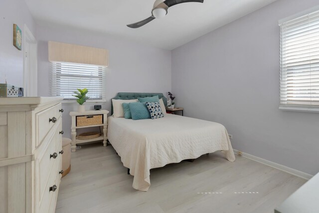 bedroom with light wood finished floors, ceiling fan, and multiple windows