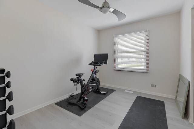 workout room featuring baseboards, ceiling fan, and light wood finished floors