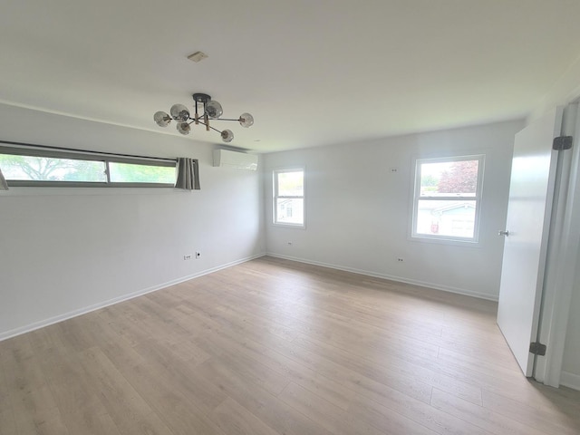 1076 Cernan Ct, Elk Grove Village, IL 60007 - empty room with a wall unit AC, a chandelier, light wood-type flooring, and baseboards