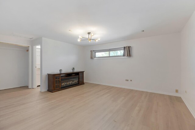 spare room featuring baseboards, an inviting chandelier, and light wood-type flooring