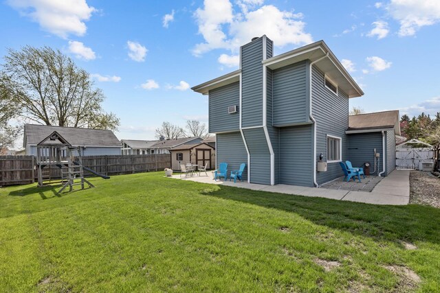 rear view of property featuring a playground, a patio, a chimney, and a fenced backyard