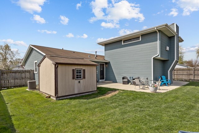back of house featuring a fenced backyard, a chimney, a lawn, and a patio area