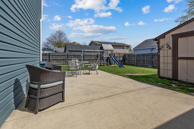 view of patio featuring a storage unit, a fenced backyard, outdoor dining area, a playground, and an outdoor structure