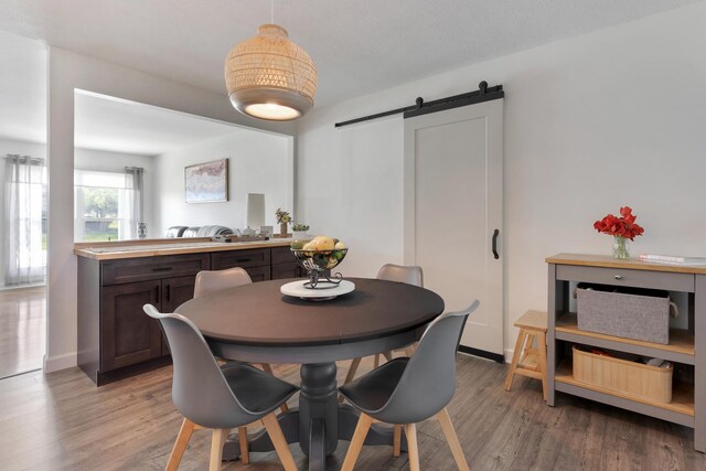 dining space featuring baseboards, a barn door, and light wood-type flooring