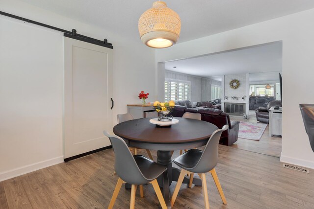 dining space featuring a barn door, light wood-style flooring, and a healthy amount of sunlight