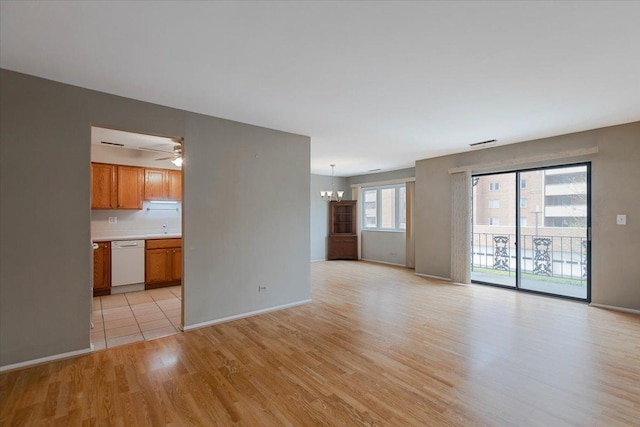unfurnished living room featuring baseboards, visible vents, an inviting chandelier, and light wood-type flooring