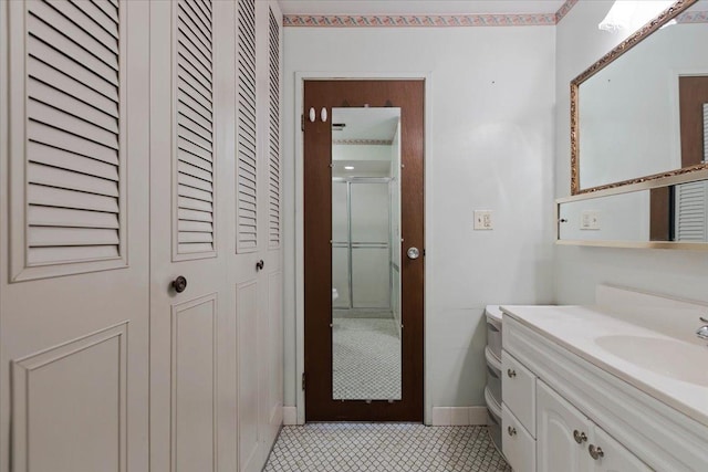 full bathroom featuring a closet, vanity, tile patterned floors, a shower stall, and baseboards