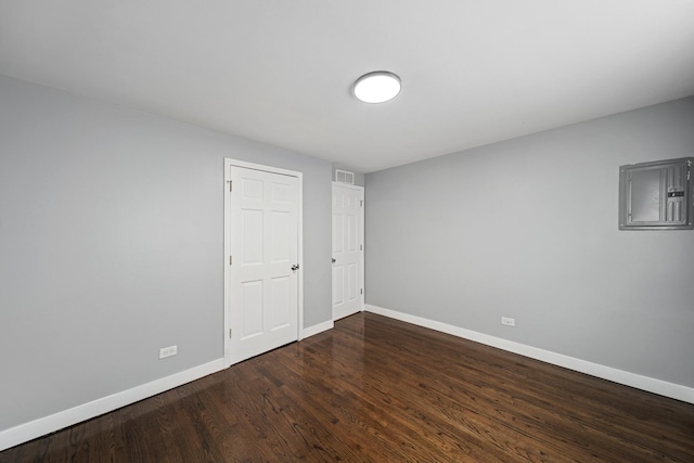 unfurnished bedroom with electric panel, dark wood-type flooring, baseboards, and visible vents