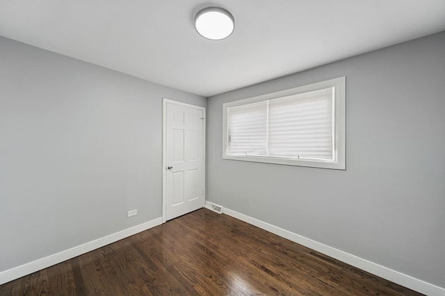 unfurnished room with dark wood-style flooring, baseboards, and visible vents