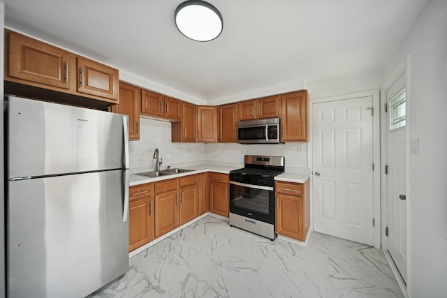 kitchen with appliances with stainless steel finishes, a sink, light marble finish flooring, and light countertops