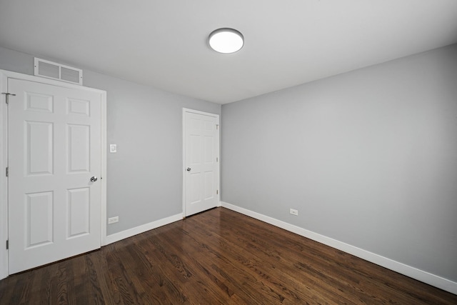 empty room with baseboards, dark wood-style floors, and visible vents