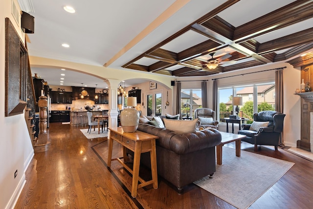 living room featuring arched walkways, ceiling fan, decorative columns, and beam ceiling