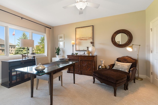 home office with baseboards, a ceiling fan, and light carpet