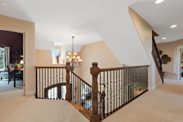 hallway with carpet flooring, baseboards, an inviting chandelier, and an upstairs landing