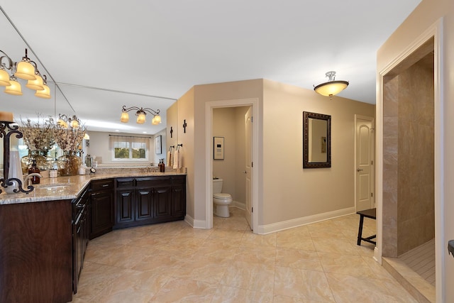 bathroom with double vanity, a sink, toilet, an inviting chandelier, and tiled shower