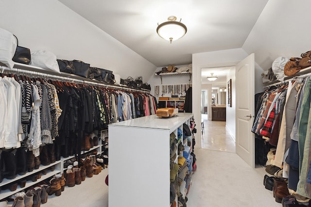walk in closet with light colored carpet and vaulted ceiling