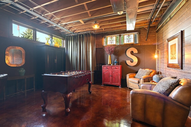 rec room featuring finished concrete floors, wood walls, and a wealth of natural light