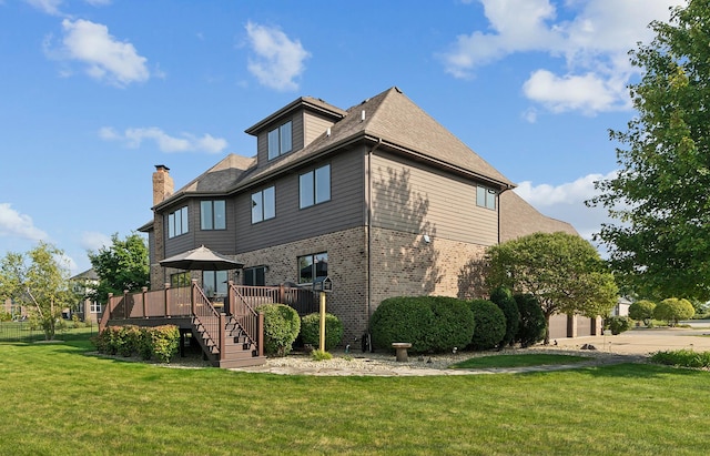 rear view of property featuring a chimney, a lawn, a deck, brick siding, and an attached garage