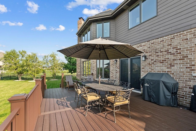 wooden terrace with a lawn, outdoor dining space, fence, and area for grilling