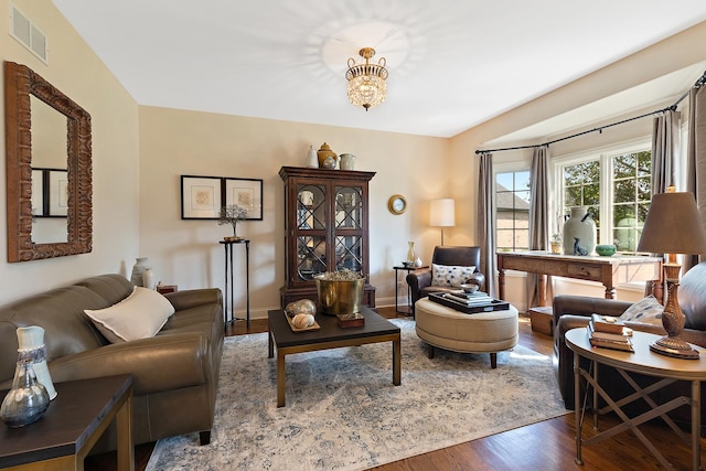 living room with visible vents, wood finished floors, and a notable chandelier