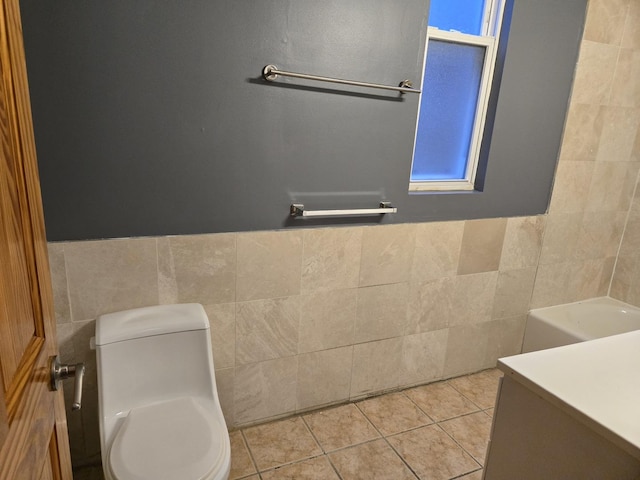bathroom with toilet, tile patterned floors, tile walls, and a wainscoted wall