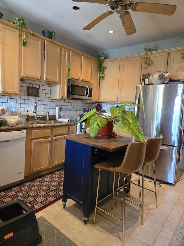 kitchen with a ceiling fan, a sink, backsplash, and stainless steel appliances