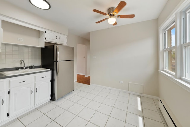 kitchen with open shelves, a sink, a baseboard radiator, freestanding refrigerator, and white cabinetry