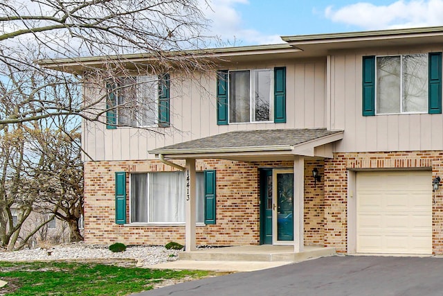 view of front facade with board and batten siding, brick siding, an attached garage, and driveway