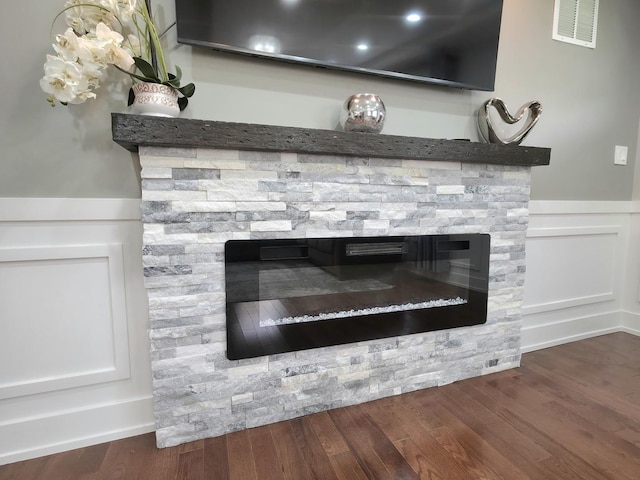 10847 Carpenter St, Mokena, IL 60448 - room details with a decorative wall, a stone fireplace, a wainscoted wall, wood finished floors, and visible vents