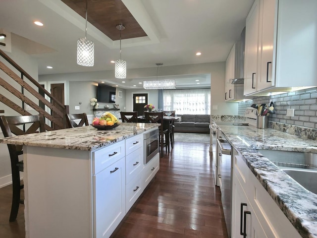 10847 Carpenter St, Mokena, IL 60448 - kitchen with a breakfast bar, open floor plan, a raised ceiling, hanging light fixtures, and stainless steel appliances