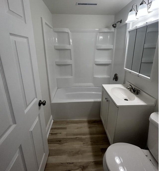bathroom with visible vents, wood finished floors, shower / washtub combination, vanity, and toilet