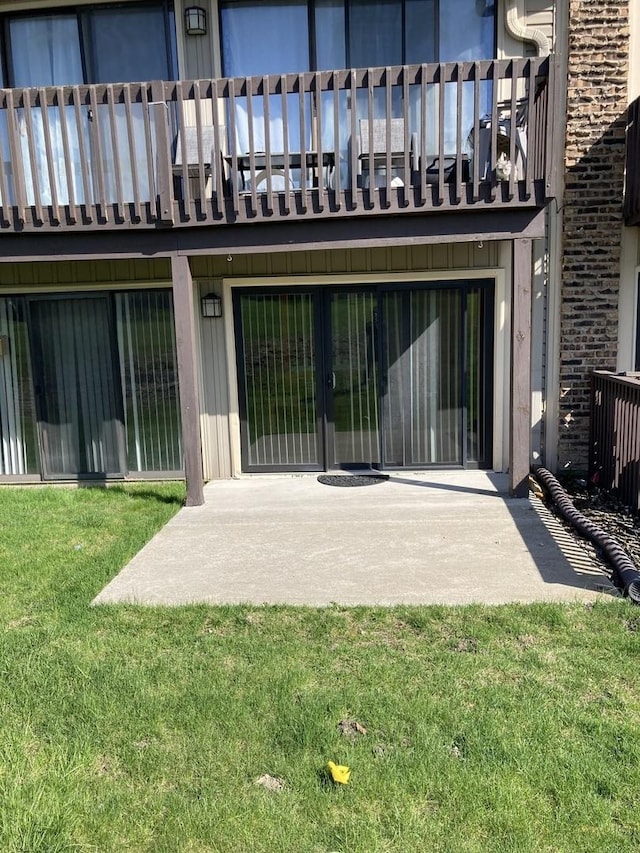 rear view of house featuring a lawn, brick siding, and a patio area