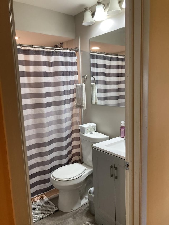 bathroom with a shower with shower curtain, toilet, wood finished floors, and vanity