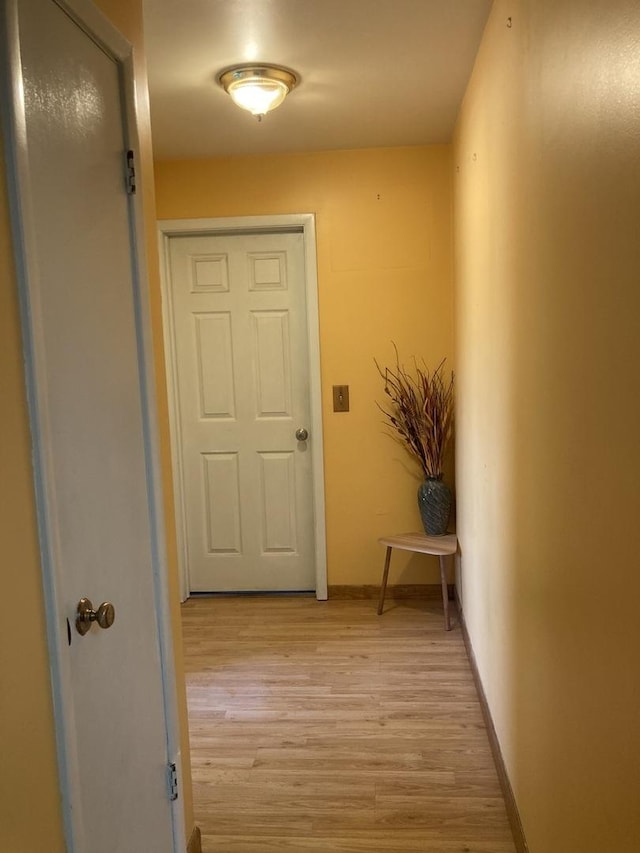 corridor featuring baseboards and light wood-style flooring
