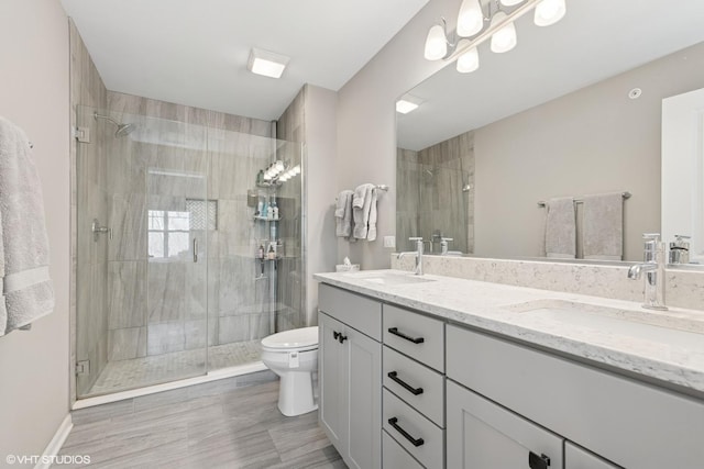 full bathroom featuring double vanity, toilet, a sink, and a stall shower