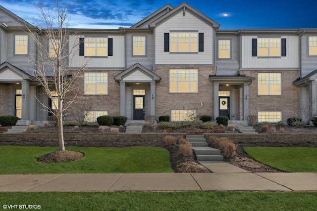 multi unit property featuring a front lawn and brick siding