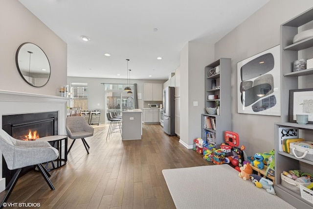 interior space with a glass covered fireplace, recessed lighting, and dark wood-style flooring