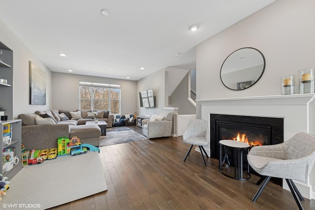living area featuring a glass covered fireplace, recessed lighting, and dark wood-style floors