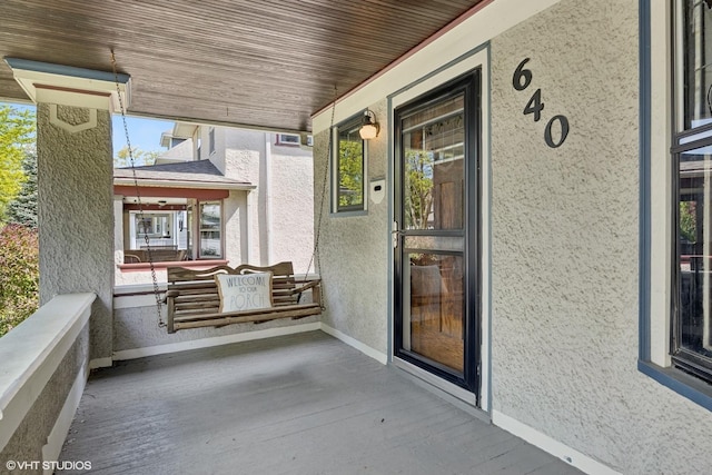 property entrance featuring covered porch and stucco siding