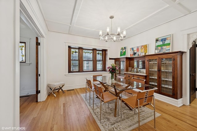 dining space with a chandelier, healthy amount of natural light, light wood-style floors, baseboards, and beamed ceiling