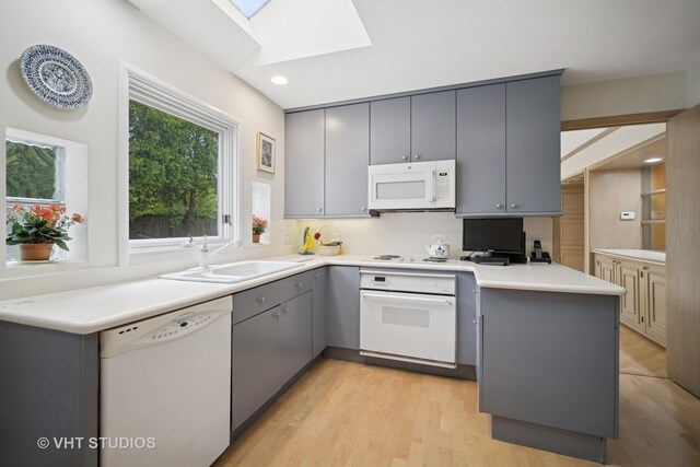 419 Sheridan Rd, Highland Park, IL 60035 - kitchen featuring white appliances, a sink, gray cabinetry, a peninsula, and a skylight