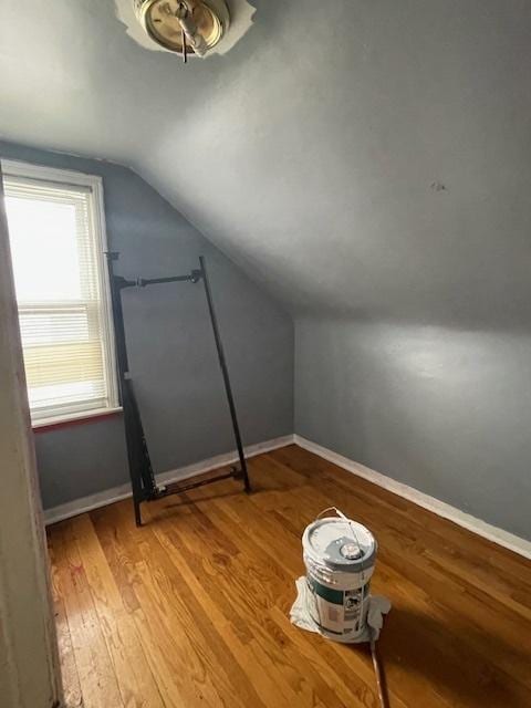 additional living space with baseboards, vaulted ceiling, and light wood finished floors