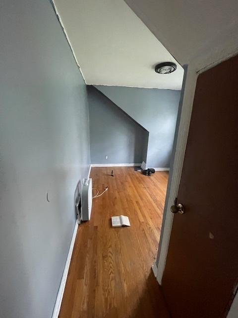 additional living space featuring baseboards and wood finished floors