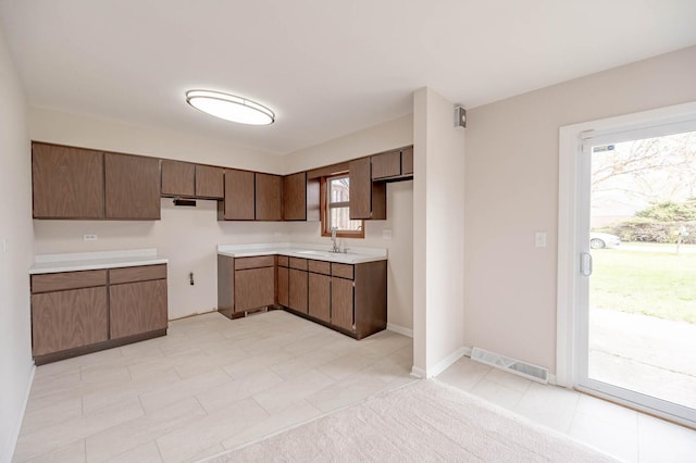 kitchen with a sink, visible vents, light countertops, light tile patterned floors, and baseboards