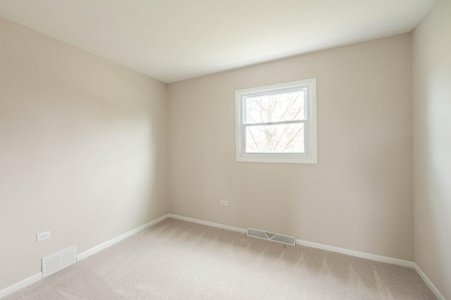 spare room featuring baseboards, visible vents, and light colored carpet