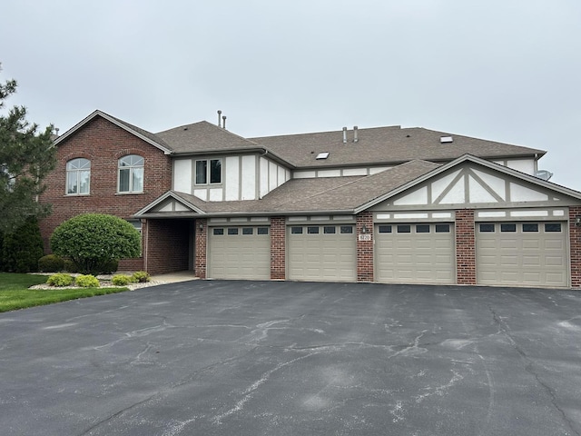 view of front of house featuring brick siding, aphalt driveway, and roof with shingles