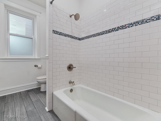 bathroom featuring baseboards, toilet, and shower / washtub combination