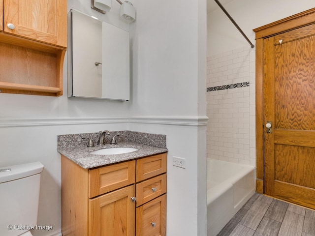 bathroom featuring toilet, tub / shower combination, wood finished floors, and vanity